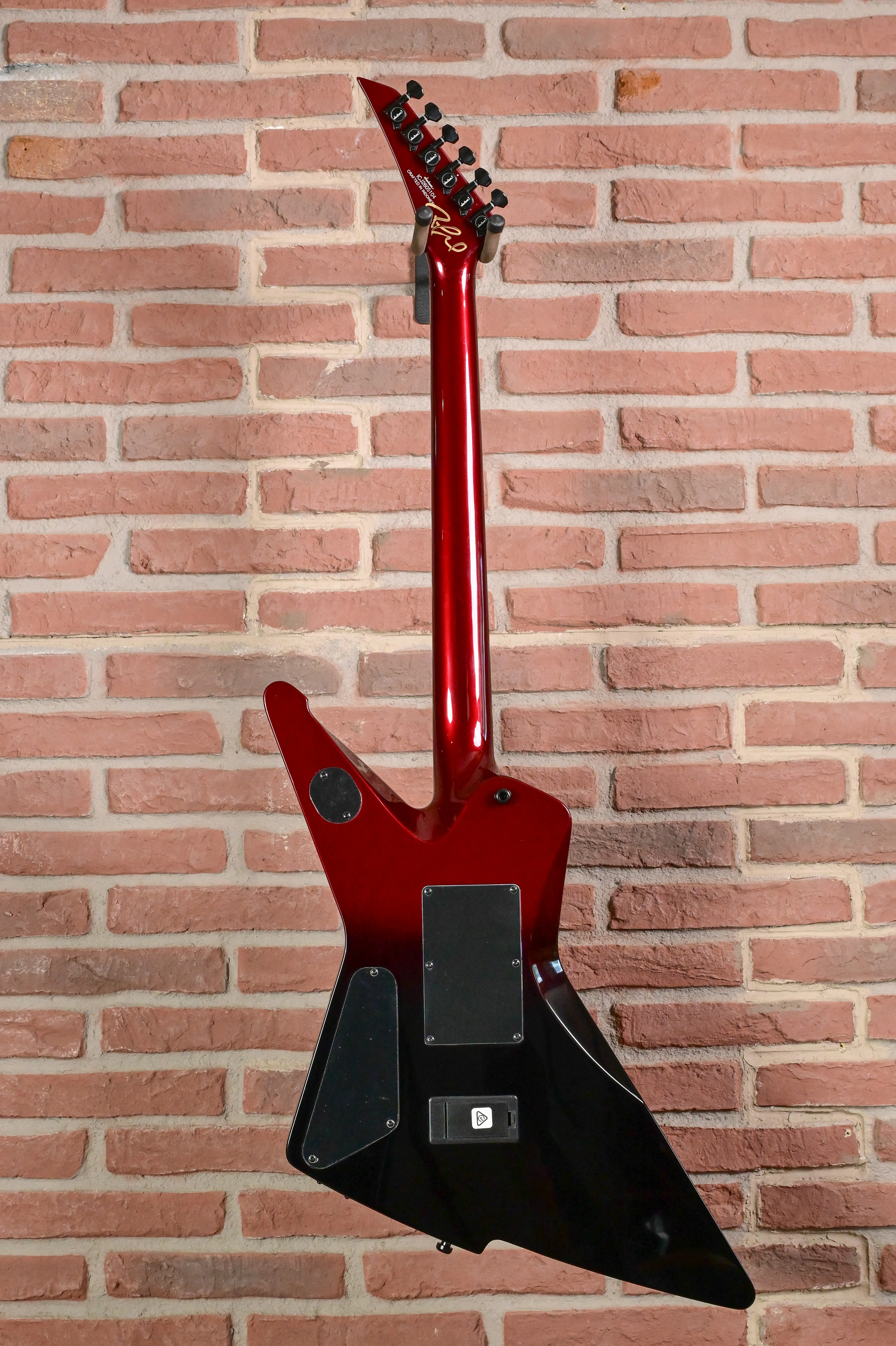E-Gitarre, Flying-V-Form, roter Korpus, schwarze Rückseite, spitze Kopfplatte