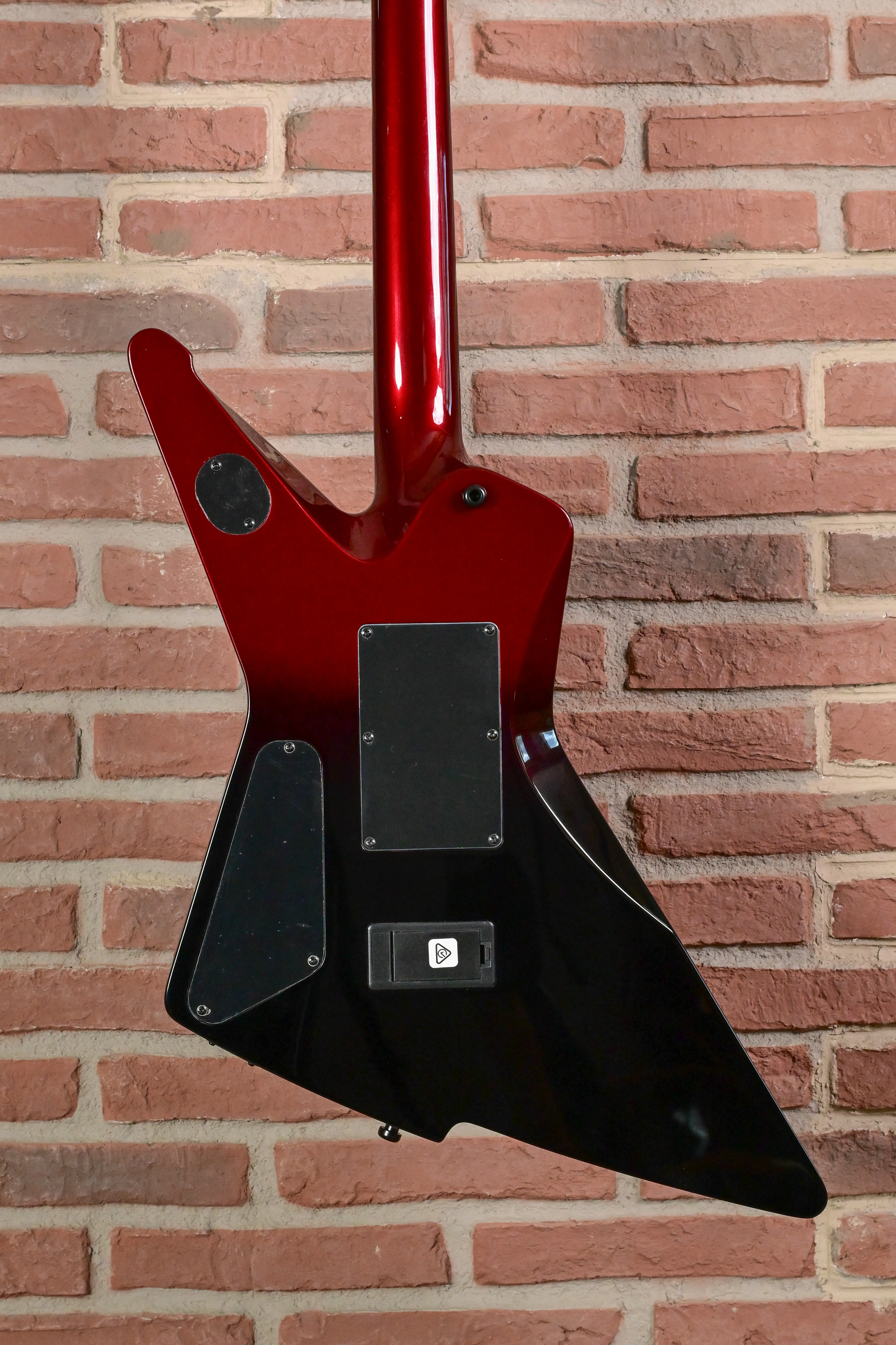 E-Gitarre, Flying-V-Form, roter Hals, schwarzer Korpus, Massivkorpus